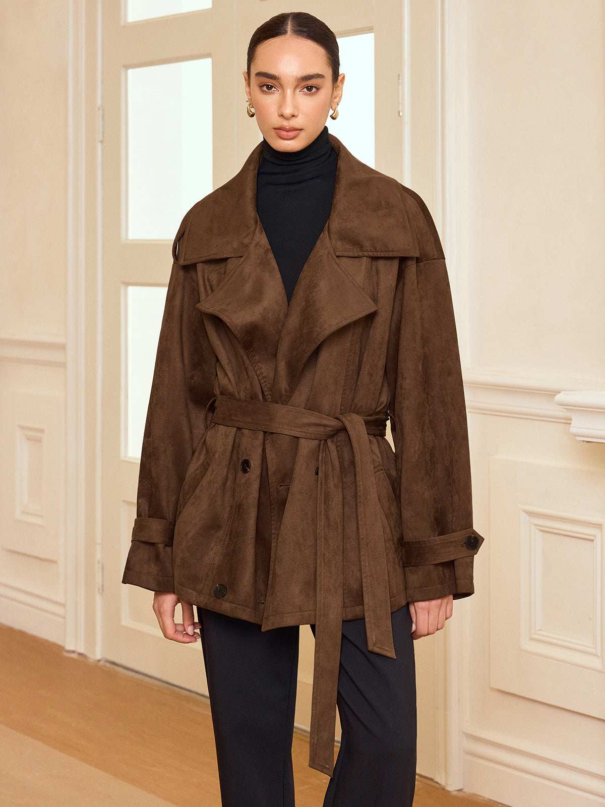 LA FINE FLEUR suede-like trench coat with belt and lapel over black turtleneck and pants.