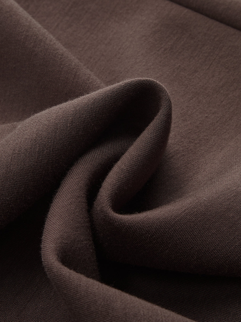 A close-up of the soft, dark brown LA FINE FLEUR pullover sweatshirt fabric and folds.