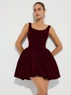 A deep burgundy velvet mini dress with bubble hem, straps, fitted bodice, and voluminous skirt.
