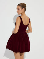 A deep red velvet mini dress with bubble hem, low back, and delicate straps.