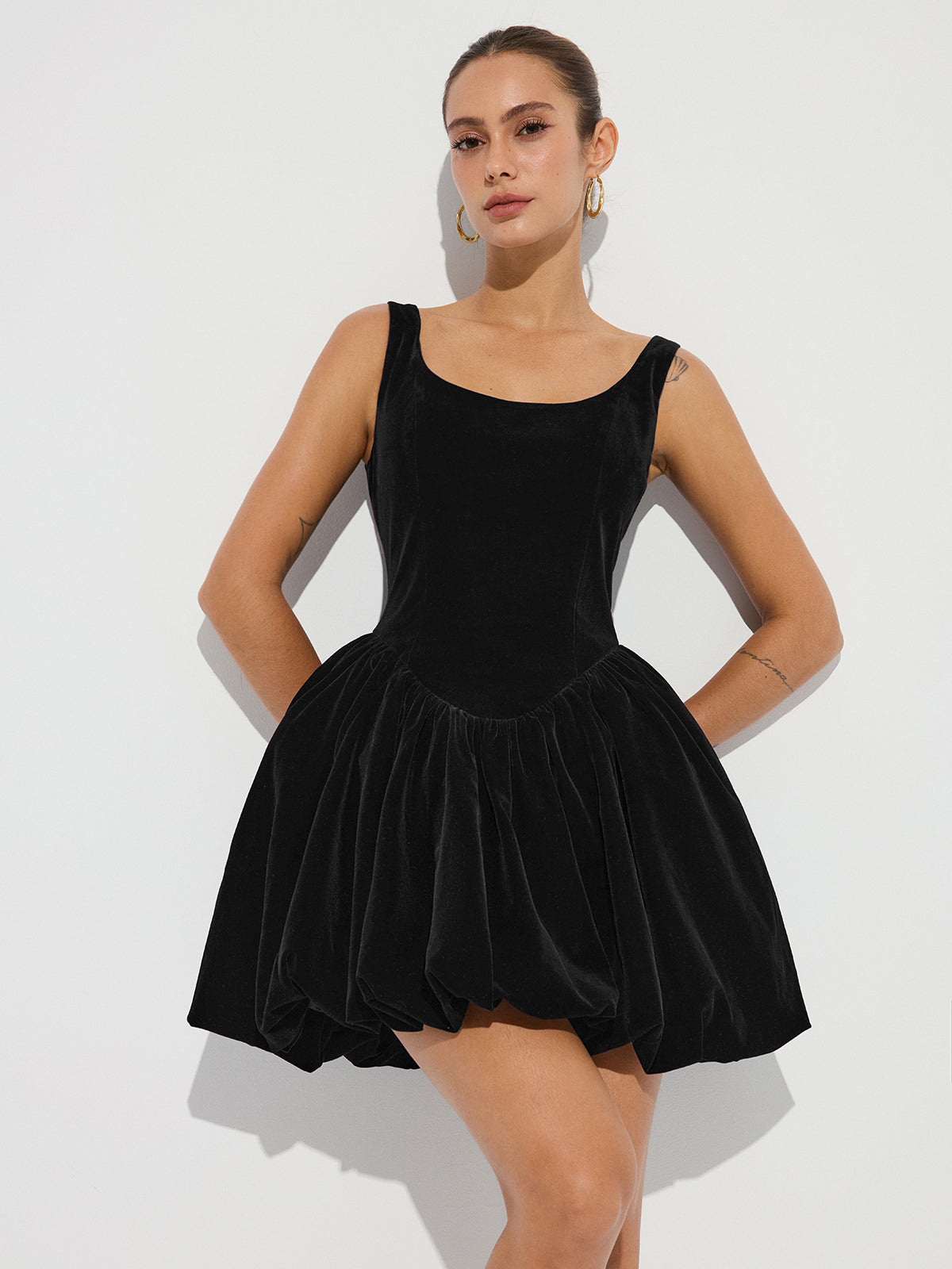 A chic, sleeveless velvet mini dress with bubble hem, fitted bodice, and flared skirt.