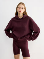 A casual hoodie with embroidered lettering, paired with matching maroon cycling shorts.