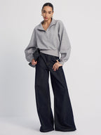 Gray LA FINE FLEUR half-zip cropped sweatshirt with oversized fit and dark wide-leg jeans.