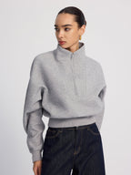 An LA FINE FLEUR half-zip cropped sweatshirt in oversized fit paired with dark blue jeans.