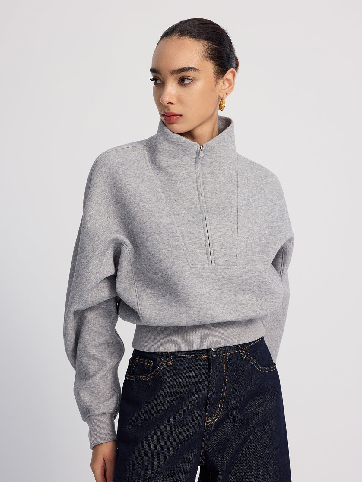 An LA FINE FLEUR half-zip cropped sweatshirt in oversized fit paired with dark blue jeans.