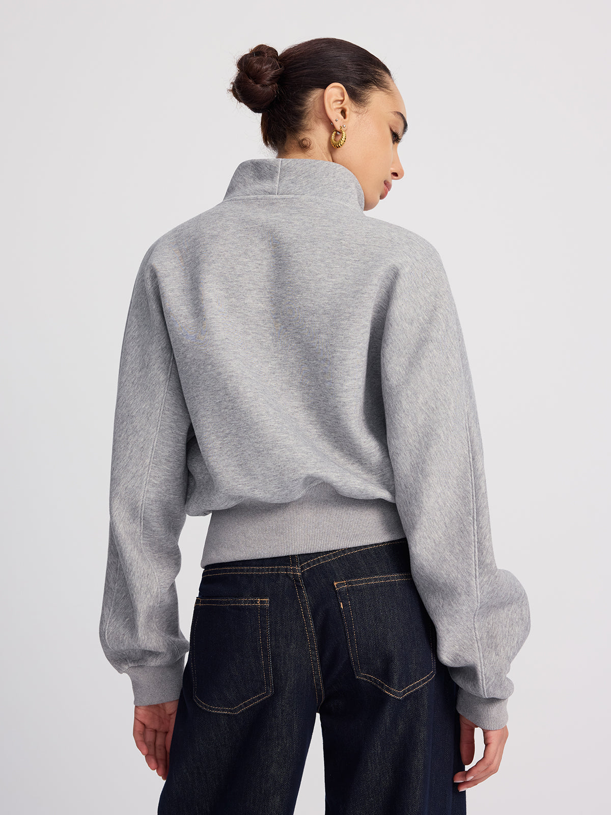 Oversized fit, half-zip cropped sweatshirt paired with dark blue jeans.