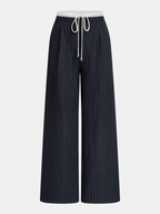 Striped wide leg trousers with white pinstripes, high-rise elastic waistband, and front drawstring.