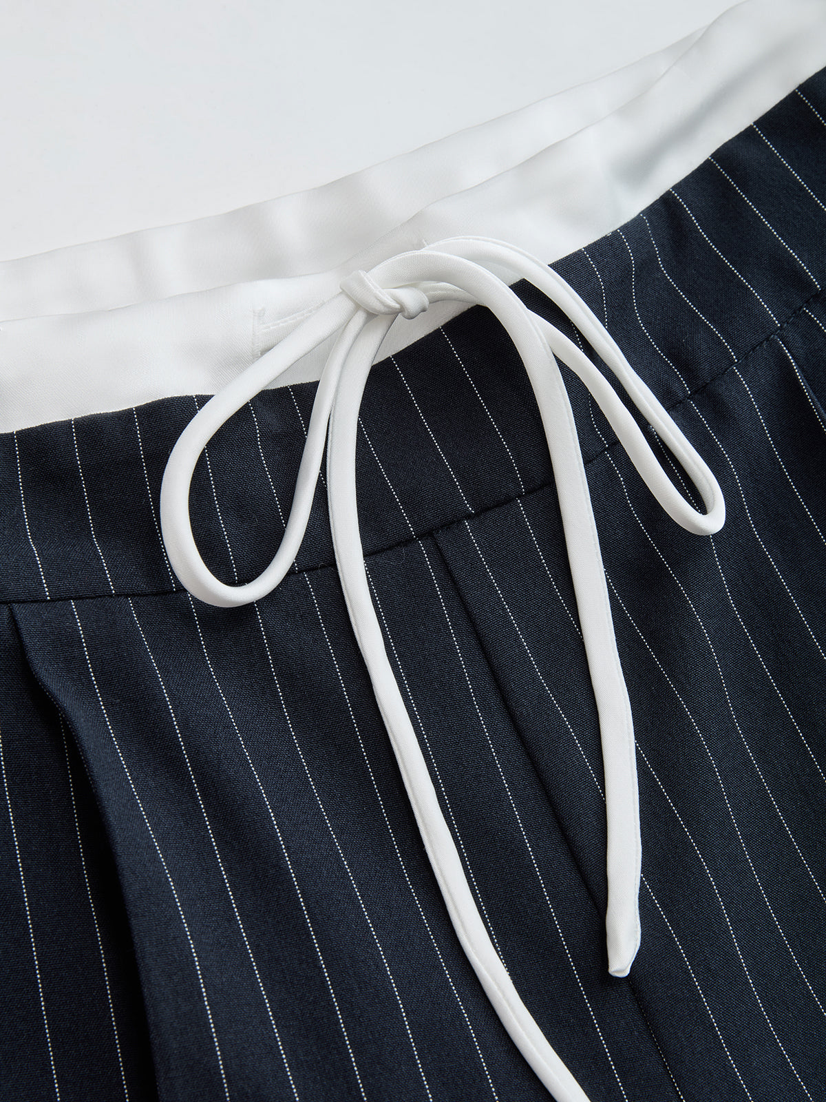 Dark navy wide leg trousers with fine vertical white stripes and a white drawstring waist.