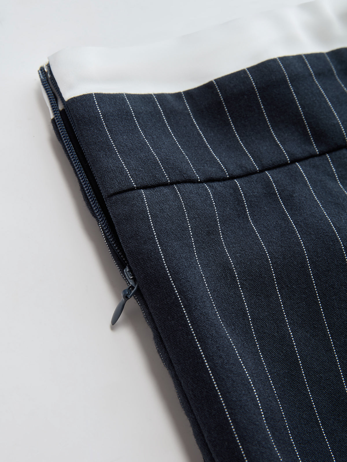 Navy blue wide leg trousers with white pinstripes, visible zipper, and solid white drawstring waist.