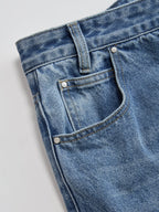 Mid-waist wide-leg jeans with asymmetric cut, blue waistband, belt loop, pocket, stitching.