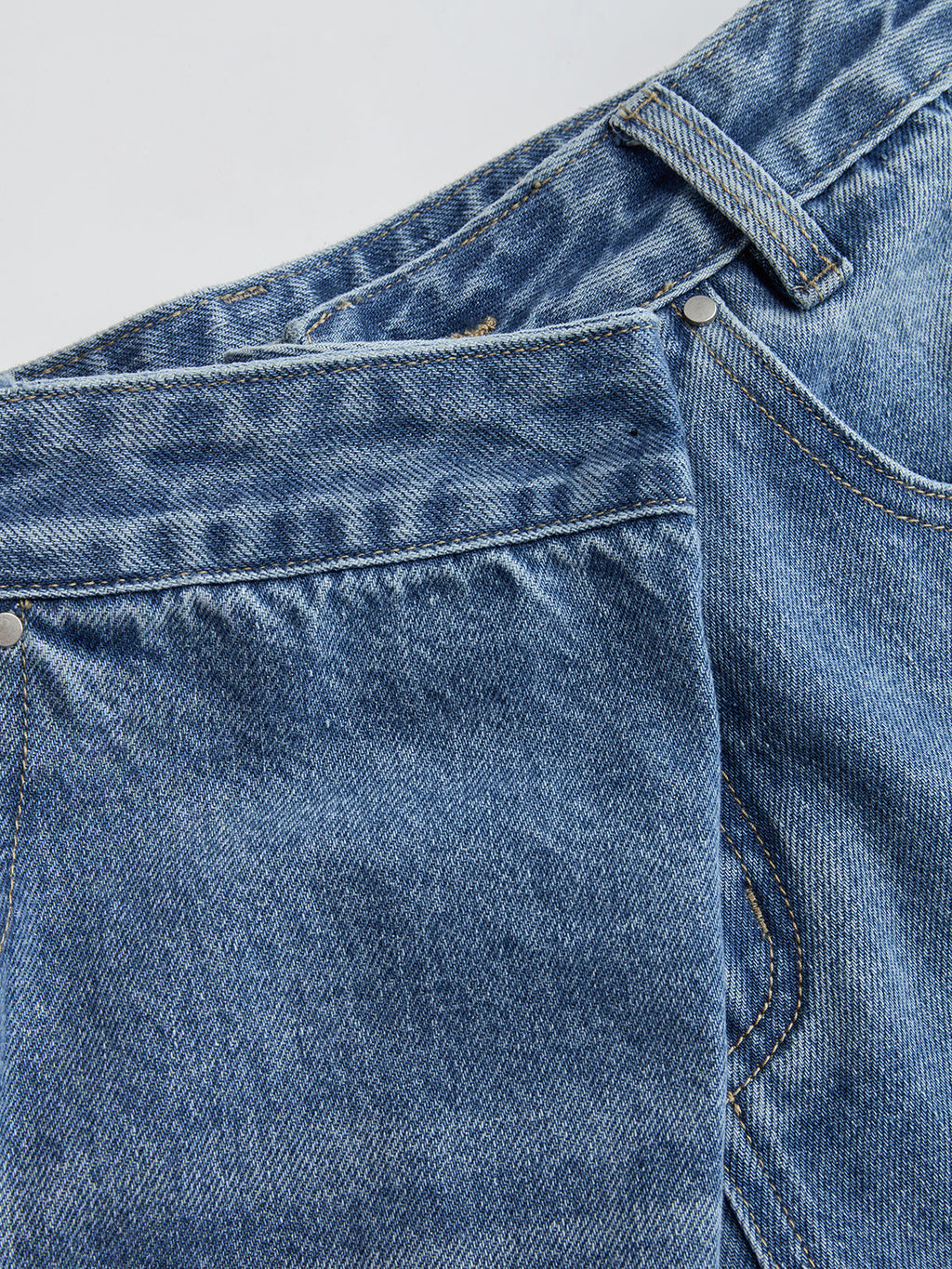 Mid-waist wide-leg jeans with asymmetric cut, defined waistband, front pocket, belt loop, and seams.