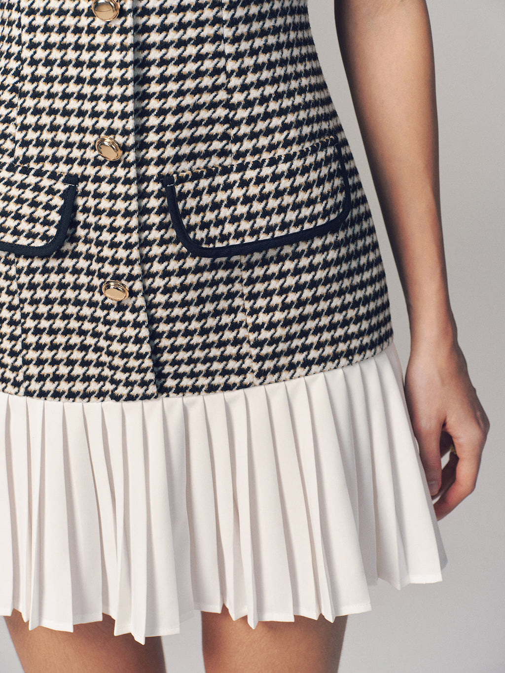The LA FINE FLEUR houndstooth sleeveless mini dress with gold buttons and pleated hem.
