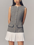 A houndstooth sleeveless mini dress with a pleated hem and gold button accents.