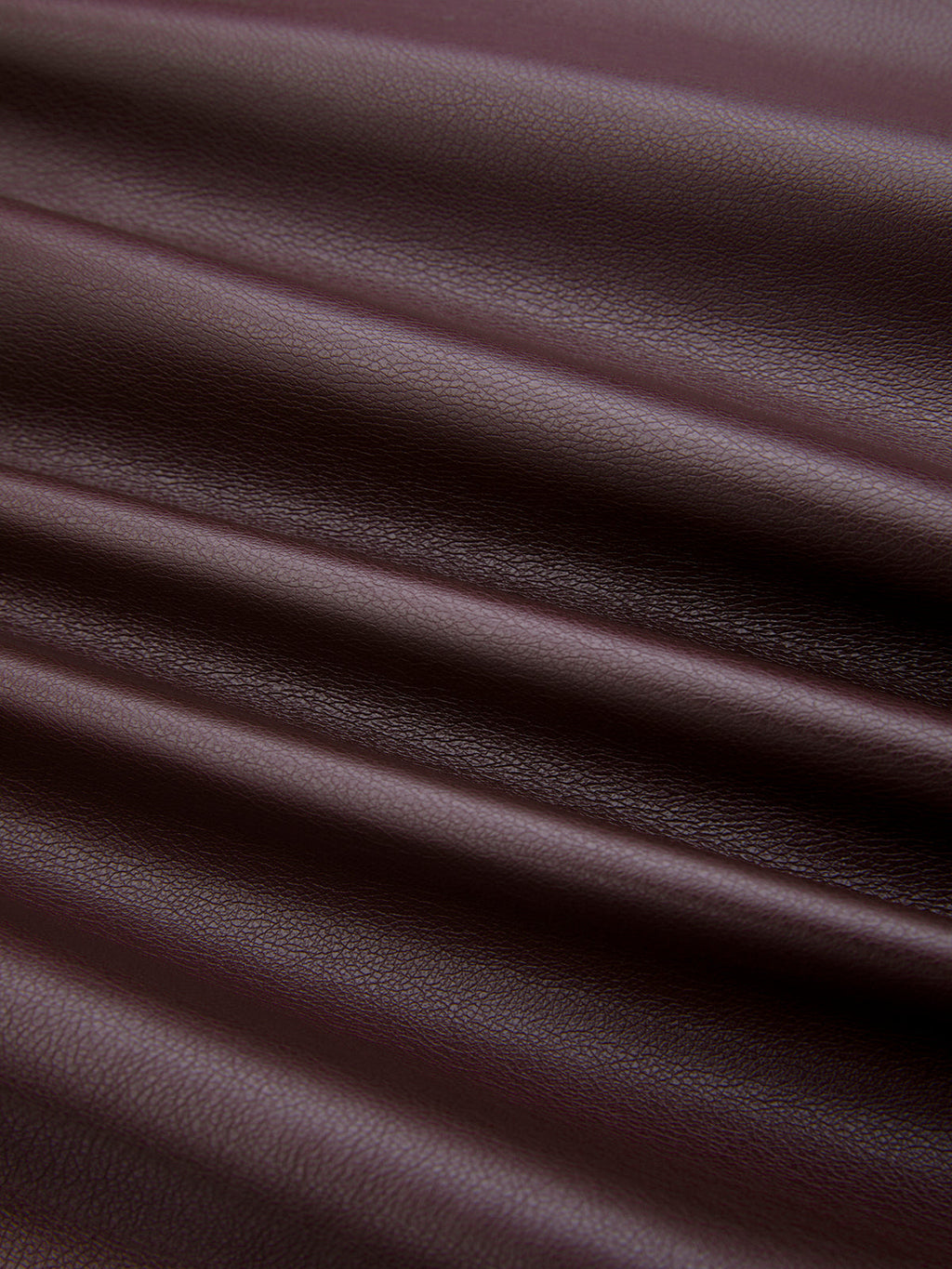 Close-up of dark brown ruched faux leather bodysuit, featuring diagonal folds and visible grain.