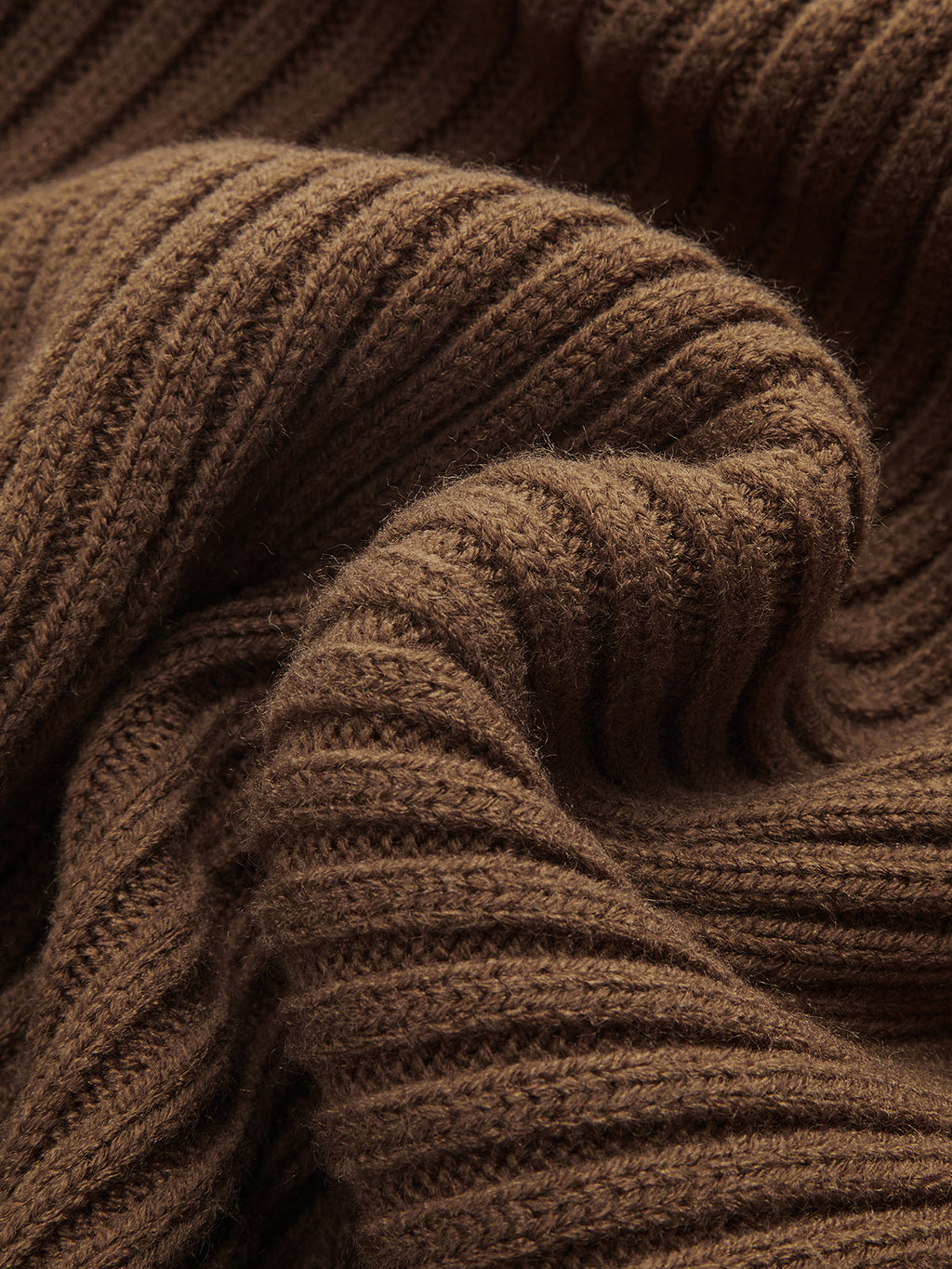 Soft brown cable-knit cropped sweater layered over a ribbed cami dress, highlighting cozy texture.