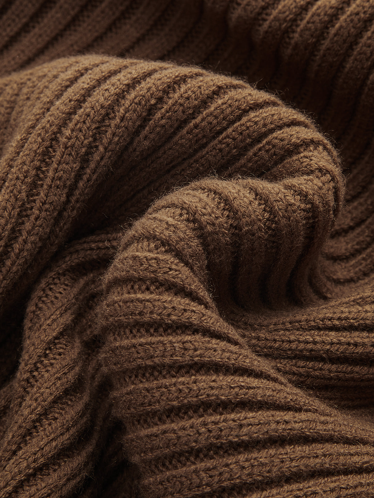 Soft brown cable-knit cropped sweater layered over a ribbed cami dress, highlighting cozy texture.