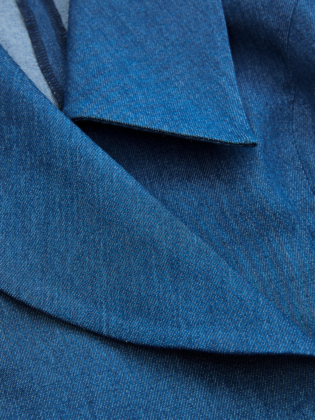 Textured collar and lapel of wrap vest with adjustable tie waist and visible stitching.