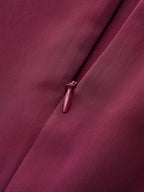 Maroon satin mock neck blouse with elegant neck tie, showcasing textured fabric and intricate weave.