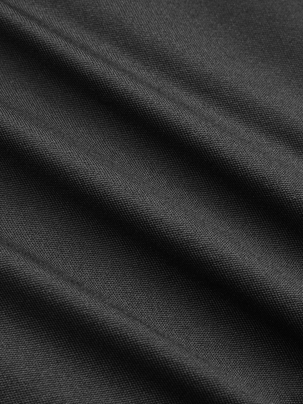 Close-up of black V-neck bodysuit with lace accents, ruching, and soft diagonal folds.