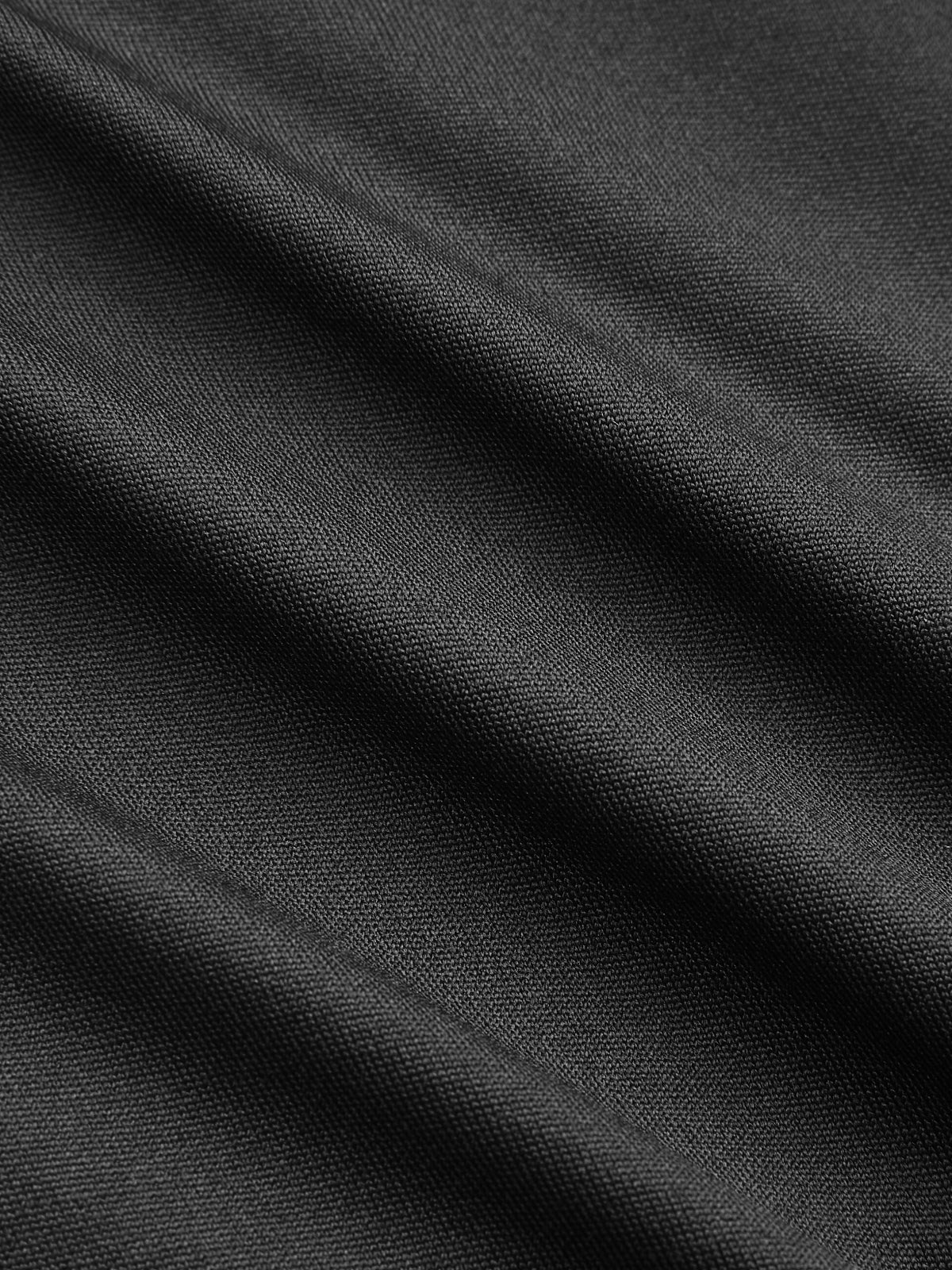 Close-up of black V-neck bodysuit with lace accents, ruching, and soft diagonal folds.