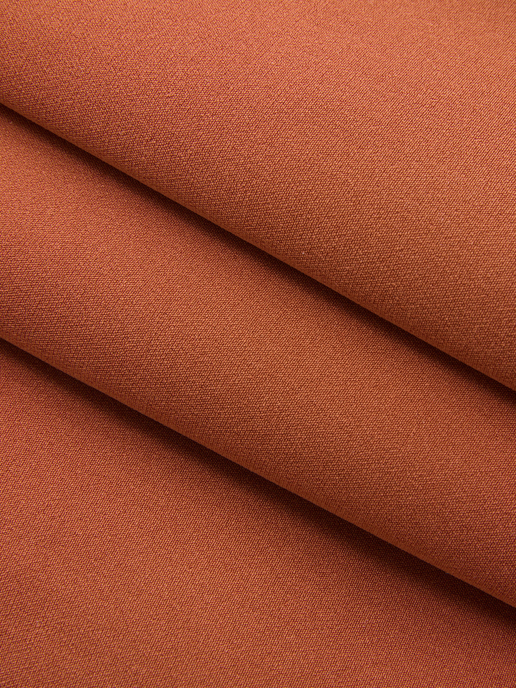Asymmetric neckline belted sleeveless mini dress in warm terracotta with fine textured weave.
