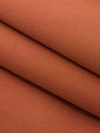 Asymmetric neckline belted sleeveless mini dress in warm terracotta with fine textured weave.