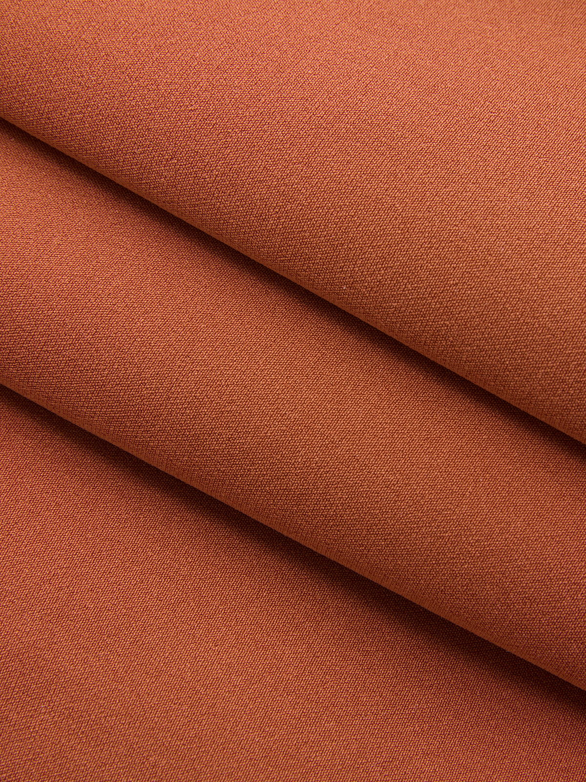 Asymmetric neckline belted sleeveless mini dress in warm terracotta with fine textured weave.