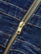 Close-up of blue denim dress with gold zipper, visible stitching, and dual buckle accents.
