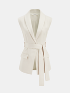 Cream belted sleeveless vest and pleated skirt set with shawl collar and pockets.