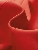 Close-up of vibrant red sleeveless blazer vest with metal detailing and elegant structured folds.