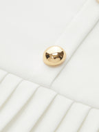 White pleated mini dress with a shiny gold metal accent at the neckline.