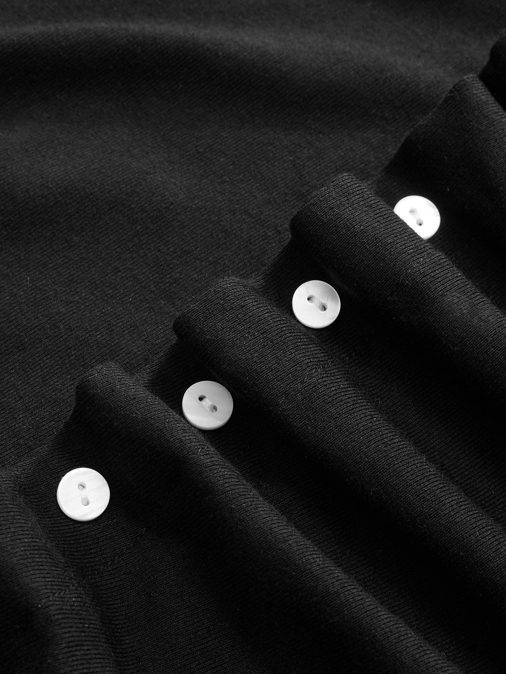 Short-sleeve dress with ruched sides, pleated black fabric, and white button accents.