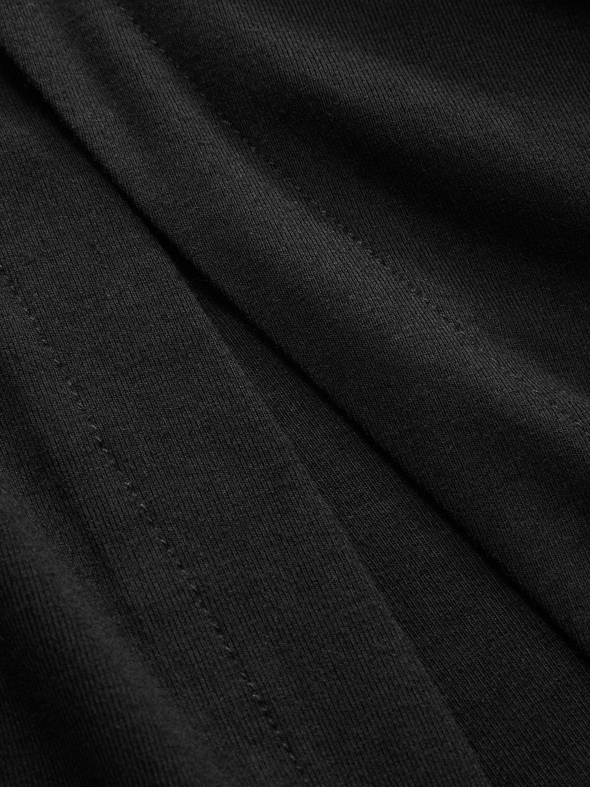 Close-up of LA FINE FLEUR black dress showing ruched sides, button details, seams, and folds.