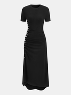 Short-sleeve black dress with ruched sides, fitted crew neck, asymmetric hem, side buttons.