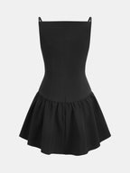 A black mini camisole dress with spaghetti straps, button accents, and a flared ruffled hem.