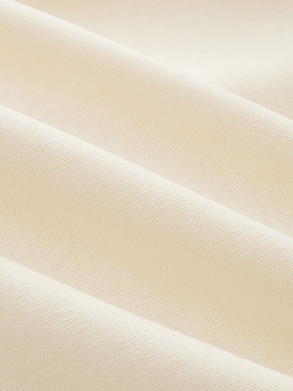Close-up of a cream linen-blend wrap dress, highlighting textured weave and contrast trim.