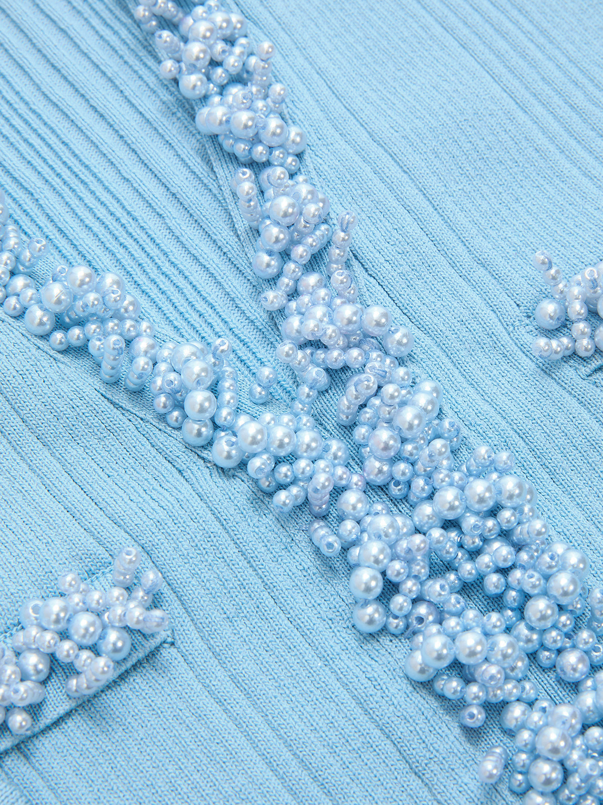 Light blue knit mini dress with pearl trim and a ruffled hem, textured detailing throughout.