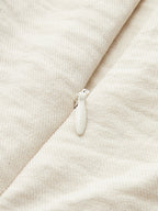 Close-up of white zipper on off-white one-shoulder jumpsuit with ruffle and contrast piping.