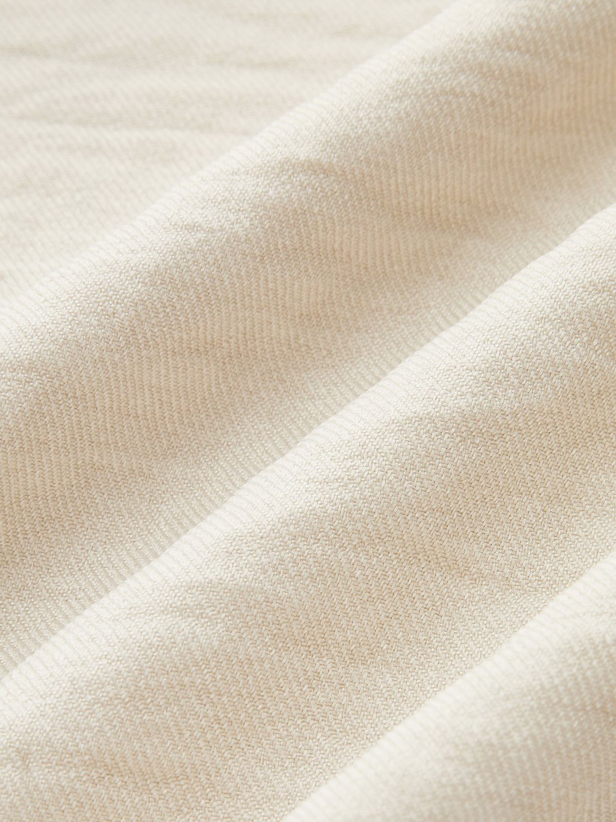 One-shoulder cream herringbone jumpsuit with ruffle detail and contrast piping, softly folded fabric.