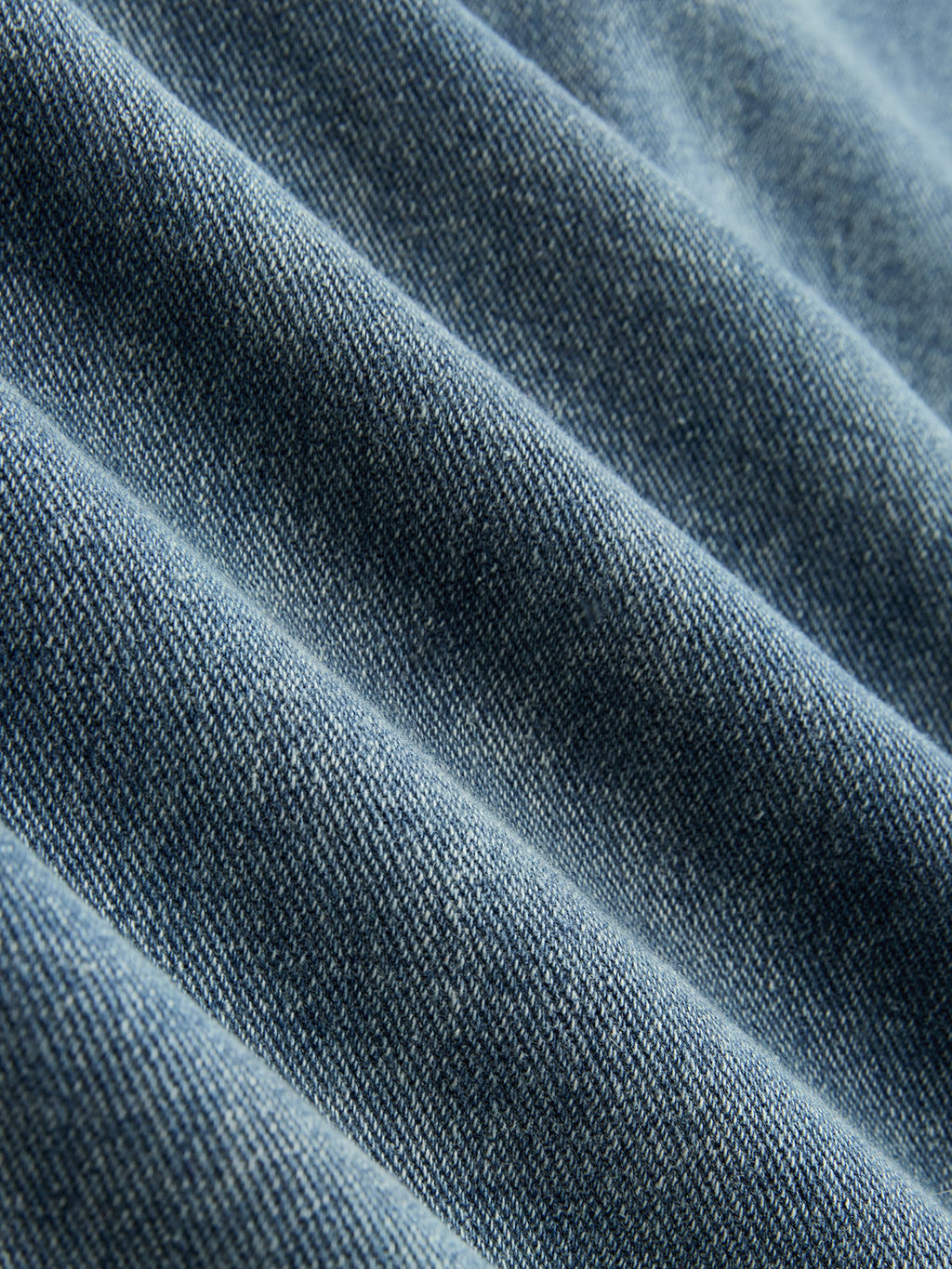 Blue denim wide-leg jeans with visible diagonal weave, featuring unique ruching and asymmetrical design.