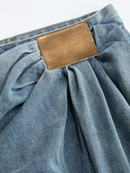 Ruched wide-leg jeans with an asymmetrical cut, gathered waistband, and brown leather back patch.