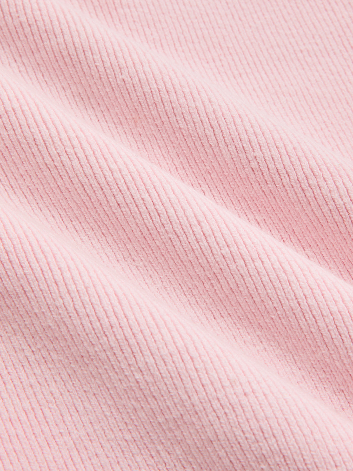 Short sleeve cardigan made of soft, light pink ribbed fabric with gentle folds and lace trim.
