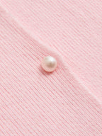 Light pink ribbed cardigan with lace trim, round pearl button, and visible vertical texture.