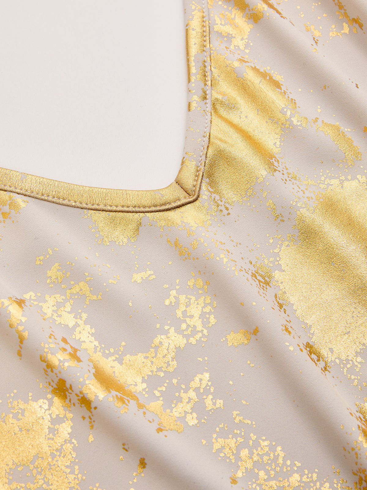 Light beige slip dress with shiny gold foil splatters and a precisely stitched V-neckline.