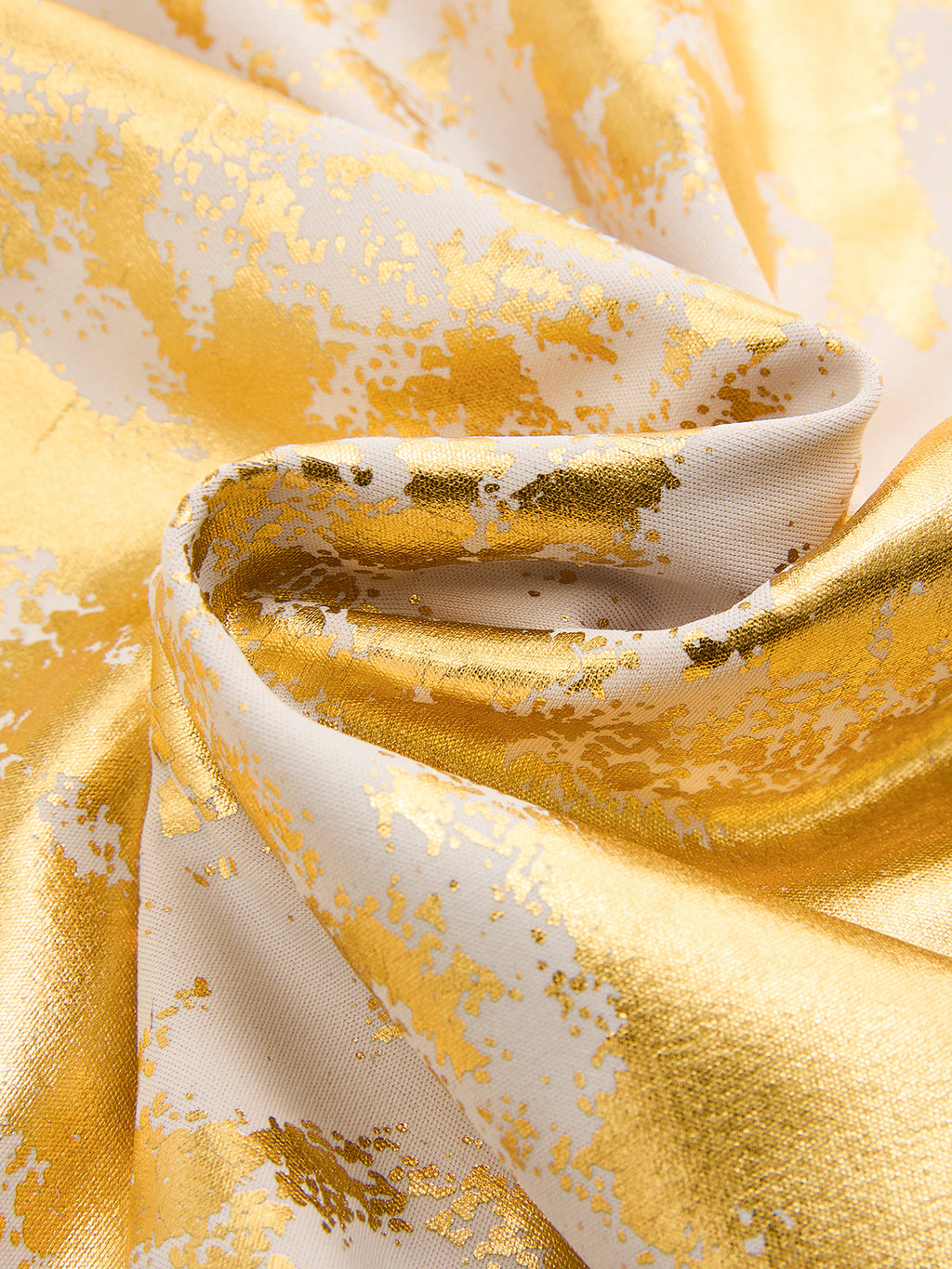 White slip dress with shiny gold foil patterns, visible folds, and a textured finish.