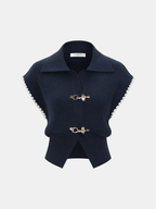 Navy blue sleeveless knit vest with collared neckline, white scalloped trim, and metal clasp.