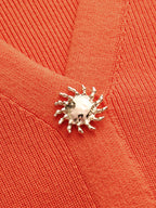 Orange knit V-neck vest with elegant silver sunburst button accents and sleeveless design.