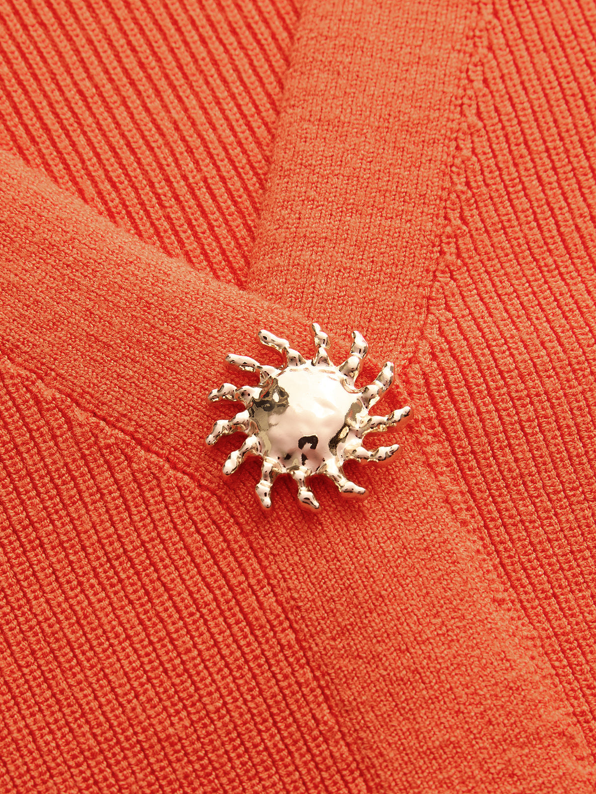 Orange knit V-neck vest with elegant silver sunburst button accents and sleeveless design.