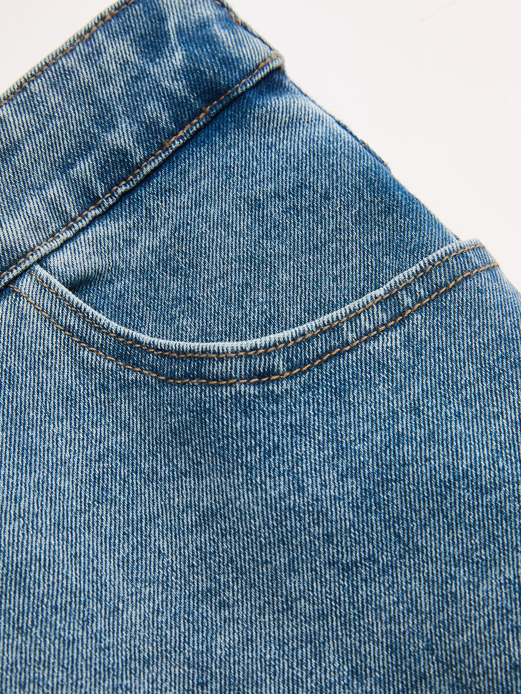 LA FINE FLEUR asymmetric high-rise straight leg jeans with front pocket and brown stitching.