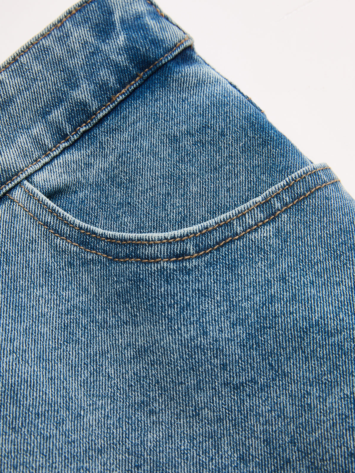 LA FINE FLEUR asymmetric high-rise straight leg jeans with front pocket and brown stitching.